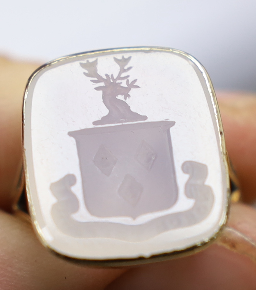 An early 20th century 9ct and white chalcedony set intaglio ring, the matrix carved with family crest and motto, size K, gross weight 5.5 grams.